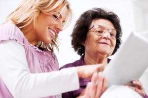 Daughter teaching her senior mother to use touchpad.